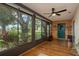 Cozy sun room with wood paneled walls, ceiling fan, and view of the landscaped yard at 1065 Tartan Dr # C, Palm Harbor, FL 34684