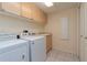 Bright laundry room with washer, dryer, tile flooring, overhead cabinets, and utility sink at 1126 Haley Ln, Dunedin, FL 34698