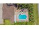 Bird's eye view of a community pool, jacuzzi, tables and lounge chairs nestled next to lush green trees at 1126 Haley Ln, Dunedin, FL 34698