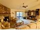 Living room with stone fireplace, ceiling fan, sliding glass doors to the patio and wooden shelving unit at 11430 Nature Trl, Port Richey, FL 34668
