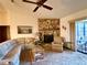 Comfortable living room featuring a stone fireplace, ceiling fan, and sliding glass doors to the patio at 11430 Nature Trl, Port Richey, FL 34668