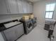 Functional laundry room with gray cabinets, modern washer and dryer, and a window at 13103 Monach Isles Dr, Riverview, FL 33579