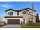 Daytime view of a two-story home featuring stone accents, a tile roof, and a charming arched entryway and a 2-car garage at 13722 Heartwood Way, Parrish, FL 34219