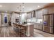 Stylish kitchen featuring stainless steel appliances, island seating, light gray cabinetry and light hardwood floors at 13722 Heartwood Way, Parrish, FL 34219