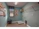 Functional laundry room with a window, shelving, and blue walls with laundry-themed decor at 13722 Heartwood Way, Parrish, FL 34219