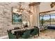 Stylish dining room with a stone accent wall, modern lighting, and a view of the pool area at 13726 Heartwood Way, Parrish, FL 34219