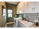 Well-organized laundry room with overhead cabinets, granite countertops, and modern appliances at 13726 Heartwood Way, Parrish, FL 34219