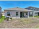 This is a backyard with green grass, a small tree, a patio with seating, and an AC unit at 152 Bright Ibis Ave, Apollo Beach, FL 33572