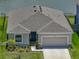 A single Gathering home has a grey shingle roof, front-entry garage and a lakeside view at 152 Bright Ibis Ave, Apollo Beach, FL 33572