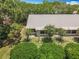 Bright home featuring a neutral roof, complemented by lush greenery and mature trees at 1556 Lynda Ln, Dunedin, FL 34698