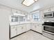 Well lit kitchen area with stainless steel appliances, and white cabinetry at 1556 Lynda Ln, Dunedin, FL 34698