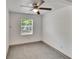 This simple bedroom features neutral paint, a ceiling fan, and a large window for natural light at 1920 E Chelsea St, Tampa, FL 33610