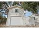 Detached garage with white door and siding, complemented by a gate and mature tree at 2015 3Rd S St, St Petersburg, FL 33705