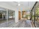 Bright sunroom with sliding glass doors leading to a patio, neutral paint and modern gray vinyl plank flooring at 2770 Keats Ter # C, Palm Harbor, FL 34684
