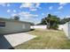 View of a fenced backyard with a concrete patio, and a grassy area with a prominent tree trunk at 2830 Anthony St, Tampa, FL 33619