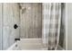 Bathroom tub and shower with stone-look tile surround and neutral-striped shower curtain at 2830 Anthony St, Tampa, FL 33619