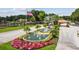 Scenic community entrance featuring a decorative fountain, vibrant flowers, and an American flag at 3351 Bristol Pl, Tarpon Springs, FL 34688