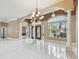 Bright and airy living area showcasing elegant chandeliers, tile floors, and views of the landscaped front yard at 3351 Bristol Pl, Tarpon Springs, FL 34688