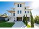 Modern white three-story home with a spacious covered parking area and well-manicured front lawn at 3752 Arkansas Ne Ave, St Petersburg, FL 33703