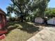 Spacious backyard featuring green grass, large trees, storage shed, and a concrete patio at 4419 Atwood Dr, Tampa, FL 33610