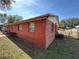 Exterior view of a backyard featuring an orange brick home exterior and green space at 4419 Atwood Dr, Tampa, FL 33610