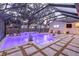 Inviting pool area with a screened enclosure, sun loungers, and lush plants, illuminated with colorful lighting for evening enjoyment at 4805 E Regnas Ave, Tampa, FL 33617