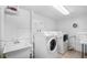 Clean laundry room features front loading washer and dryer, utility sink and storage with bright lighting and tiled floor at 5130 Brittany S Dr # 604, St Petersburg, FL 33715