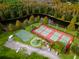 An aerial view of community amenities featuring tennis courts, a basketball court, and a playground adjacent to a pond and wooded area at 5524 Salem Square N Dr, Palm Harbor, FL 34685