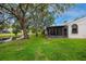 Exterior view of home showing the sunroom, lawn, and a serene pond surrounded by trees at 5524 Salem Square N Dr, Palm Harbor, FL 34685