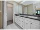 Well-lit bathroom featuring a double sink vanity, closet, and a large mirror at 5524 Salem Square N Dr, Palm Harbor, FL 34685