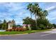 Community entrance featuring a decorative sign, lush flowers, and manicured landscaping at 5524 Salem Square N Dr, Palm Harbor, FL 34685