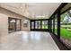 Large sunroom with tile flooring, a ceiling fan, and views of the pond and lush landscaping at 5524 Salem Square N Dr, Palm Harbor, FL 34685