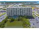 Scenic view of the condo building, pool, lake, and parking area with mature trees surrounding at 7050 Sunset S Dr # 1401, South Pasadena, FL 33707