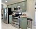 Kitchen featuring stainless steel appliances, green cabinets, granite countertops, and backsplash at 7360 Ulmerton Rd # 16A, Largo, FL 33771