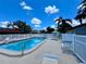 Relaxing community pool with blue water, lounge chairs, and a secure white fence for safety and privacy at 7360 Ulmerton Rd # 16A, Largo, FL 33771