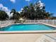 Refreshing community pool surrounded by a white fence, featuring clear water and lounge seating for residents' enjoyment at 7360 Ulmerton Rd # 16A, Largo, FL 33771