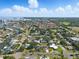 Expansive aerial view of a residential community featuring canals, golf course, palm trees, and sunny blue skies at 75 New Jersey Dr, Dunedin, FL 34698