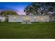Twilight backyard view featuring lush lawn, patio seating, and soft exterior lighting enhances outdoor ambience at 75 New Jersey Dr, Dunedin, FL 34698
