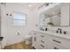Bright bathroom featuring double sink vanity, wood-look flooring, and decorative lighting at 75 New Jersey Dr, Dunedin, FL 34698