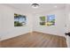 Bright bedroom with two windows, wood-look flooring, and white walls at 75 New Jersey Dr, Dunedin, FL 34698