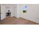 Bedroom features wood-look floors, a window with an outdoor view, and a glimpse into adjacent dining area at 75 New Jersey Dr, Dunedin, FL 34698