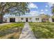 Charming single-story home featuring a well-manicured lawn, a paved walkway, and a welcoming front door at 75 New Jersey Dr, Dunedin, FL 34698