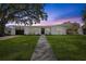 Charming single-story home featuring a well-manicured lawn, a paved walkway, and a welcoming front door at twilight at 75 New Jersey Dr, Dunedin, FL 34698