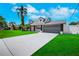 Charming home featuring a manicured lawn, mature palm trees, and a spacious two-car garage at 8711 Thornwood Ln, Tampa, FL 33615