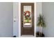 Stylish front door with glass insert and a welcoming floral wreath, enhanced by a decorative potted plant at 8916 Windlass Cv, Parrish, FL 34219