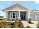 Inviting front porch with stone accents, white columns, rocking chairs, and a beautifully landscaped garden at 8916 Windlass Cv, Parrish, FL 34219