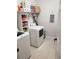 Functional laundry room with shelving, white appliances, and light tile flooring at 8916 Windlass Cv, Parrish, FL 34219