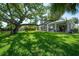 Sprawling backyard featuring a grand tree, manicured lawn, and serene outdoor living spaces at 8927 Key West Island Way, Riverview, FL 33578