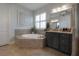 This bathroom showcases a soaking tub, gray vanity, and a contemporary mirror at 8927 Key West Island Way, Riverview, FL 33578