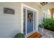 Inviting blue front door with glass panes and a wreath, complemented by lush greenery and a welcoming doormat at 8927 Key West Island Way, Riverview, FL 33578